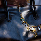 Gold charm bracelet with various charms on a textured black surface