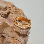 Gold ring with embedded stones on a textured stone surface