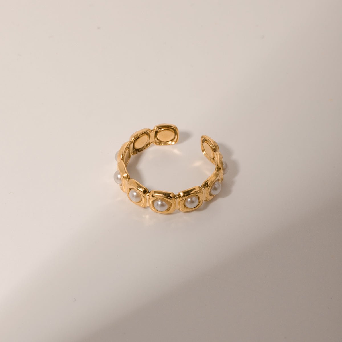 Gold bracelet with pearl-like beads on a beige background