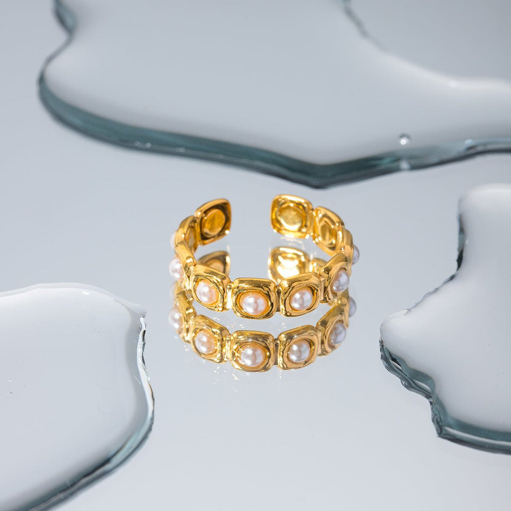 Gold ring with pearl-like stones on a white background