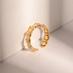 Gold ring with embedded pearls on a light beige background