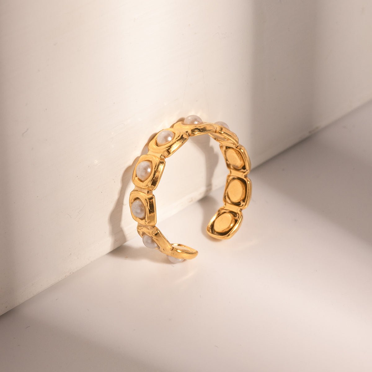 Gold ring with embedded pearls on a light beige background