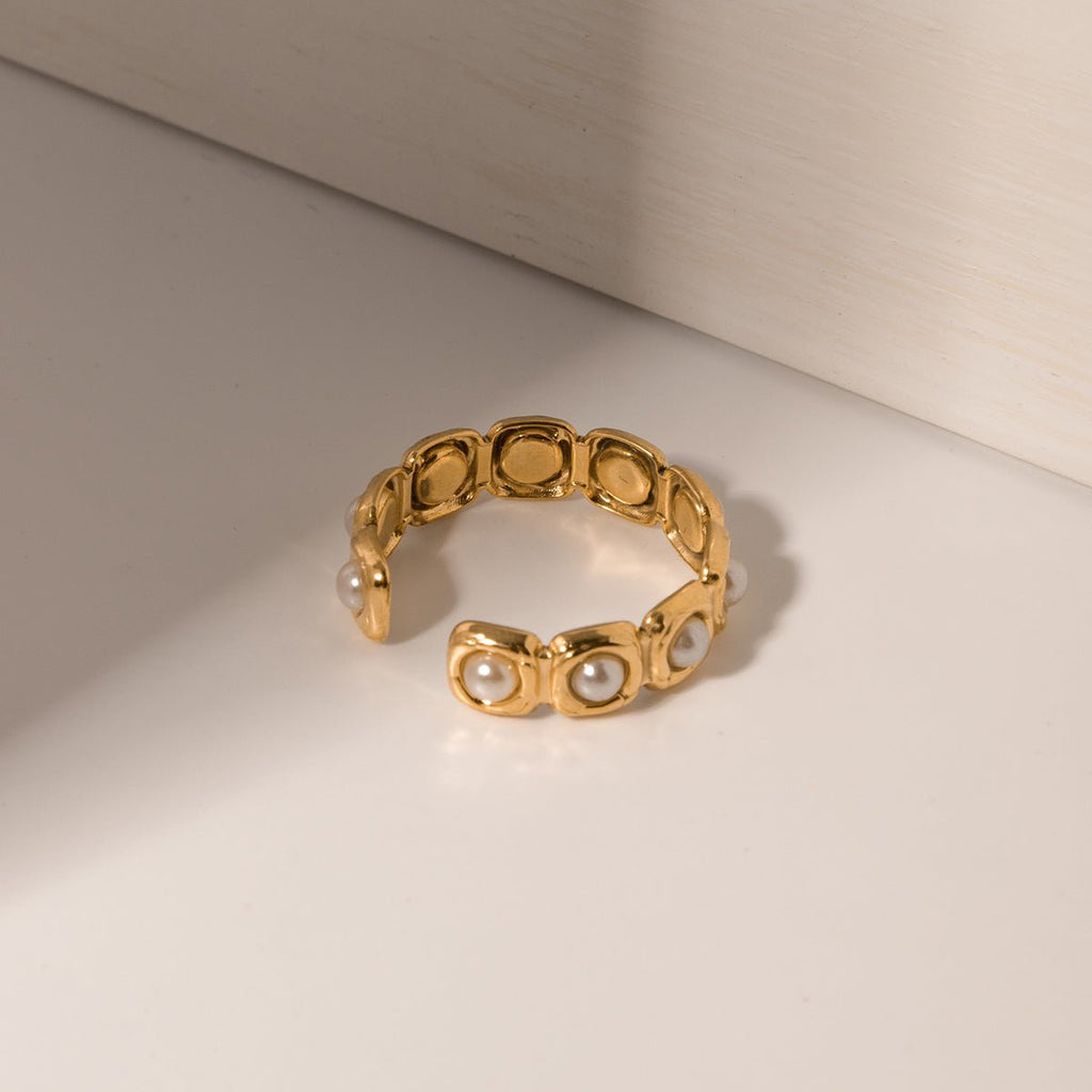 Gold ring with pearls on a light beige background