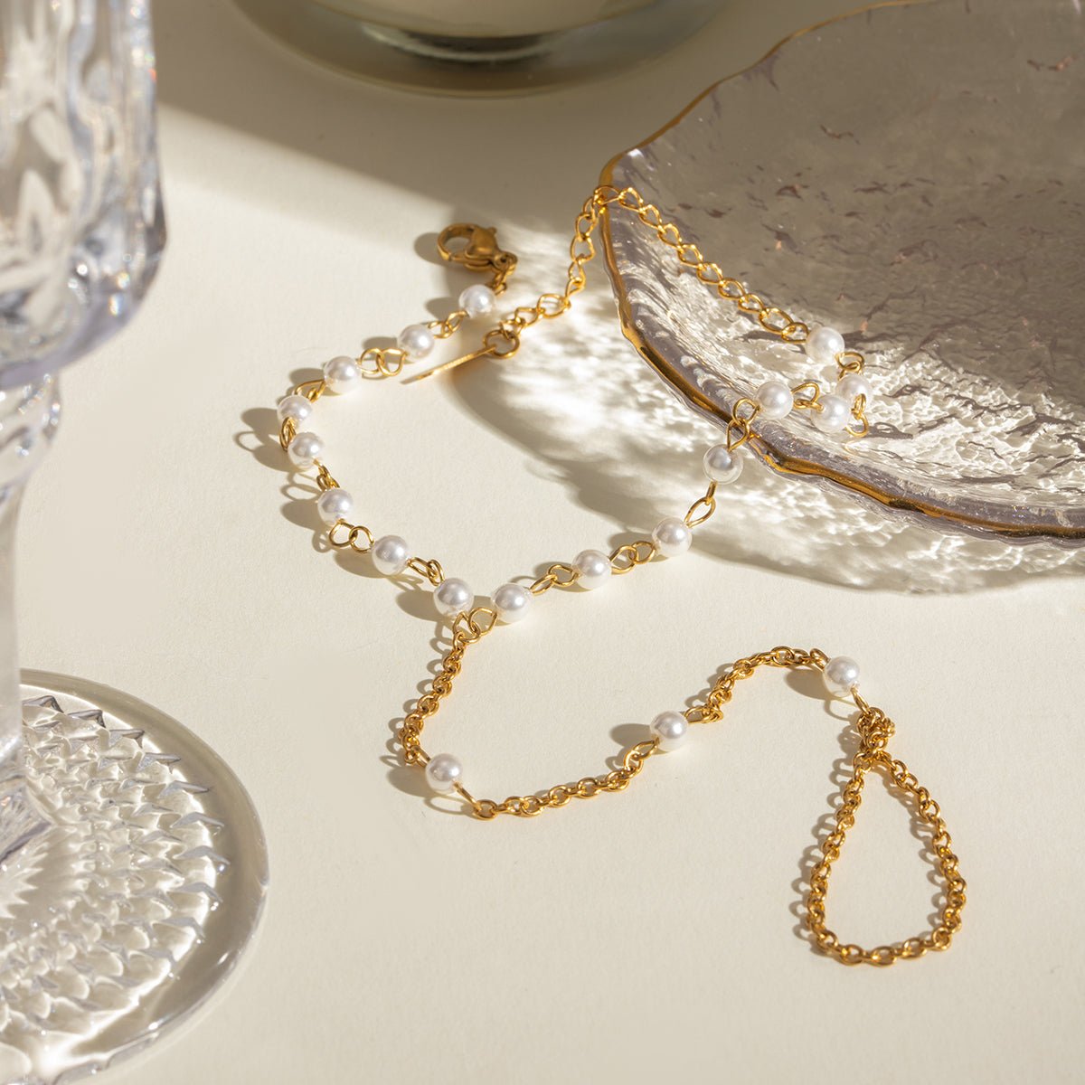 Gold chain necklace with pearls on a textured surface