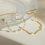 Gold chain and pearl necklace on a textured white surface
