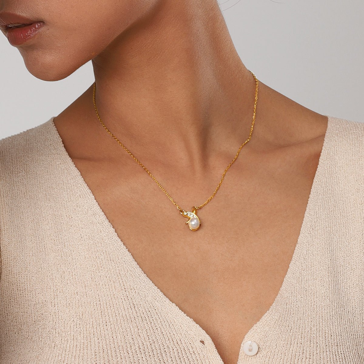 Gold necklace with a pearl pendant on a neutral background