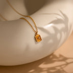 Gold necklace with a pendant on a beige surface