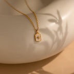Gold necklace with a pendant on a neutral background