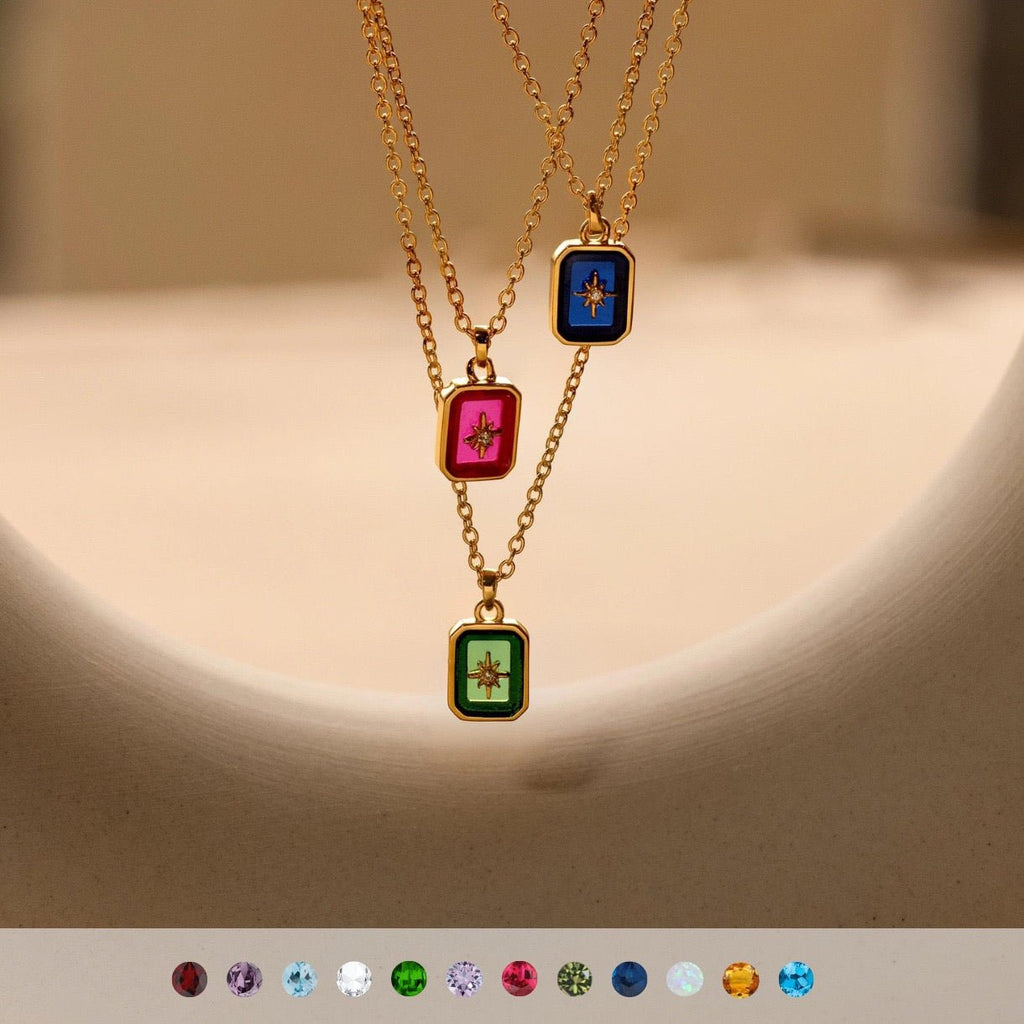 Three gold necklaces with colorful gemstones on a beige background