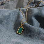 Gold necklace with a green pendant on denim fabric