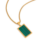 Gold necklace with a green stone pendant on a white background