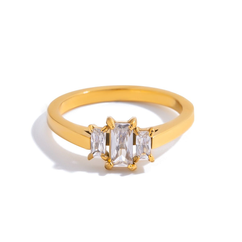 Gold ring with three clear gemstones on a white background