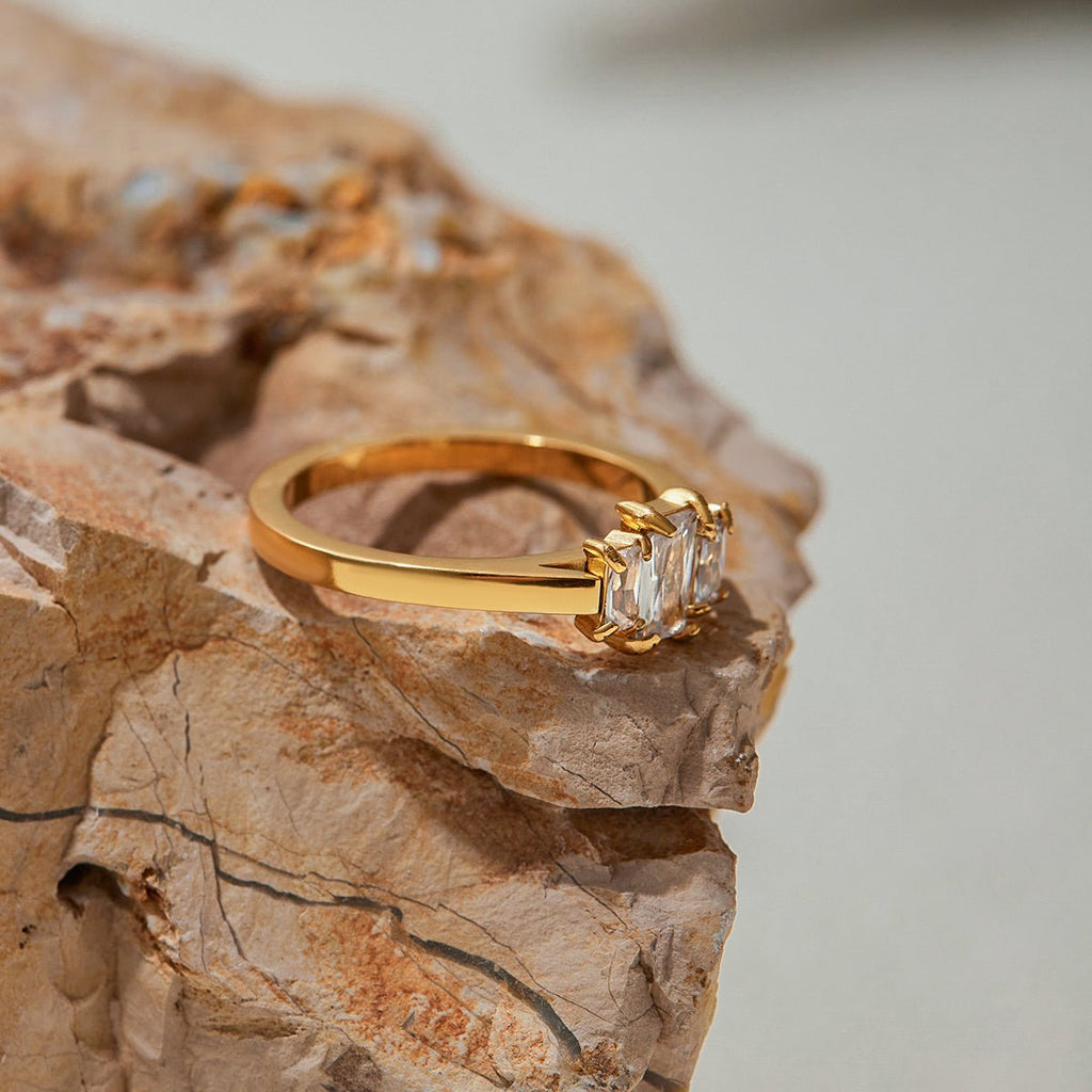 Gold ring with three diamonds on a textured stone surface