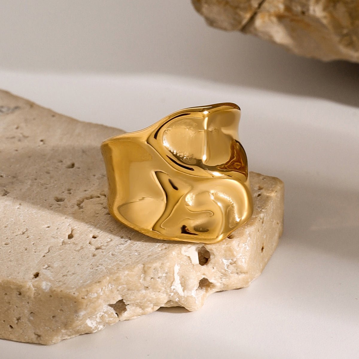 Gold ring on a textured stone surface with a neutral background