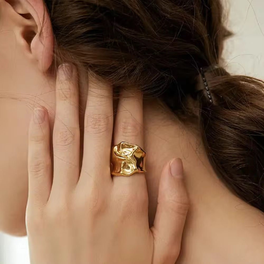 Close-up of a hand wearing a gold ring with hair partially covering the face.
