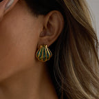 Gold and green earrings worn by a person with long hair.