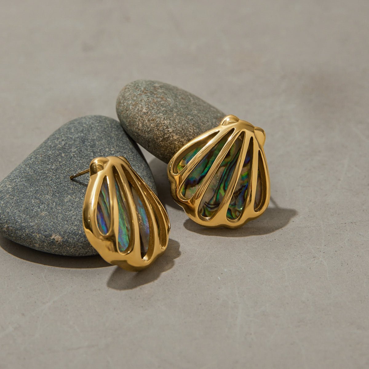 Gold earrings with multicolored stone inlay on gray stones