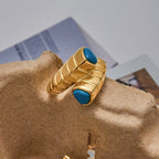 Gold ring with blue stones on a textured surface