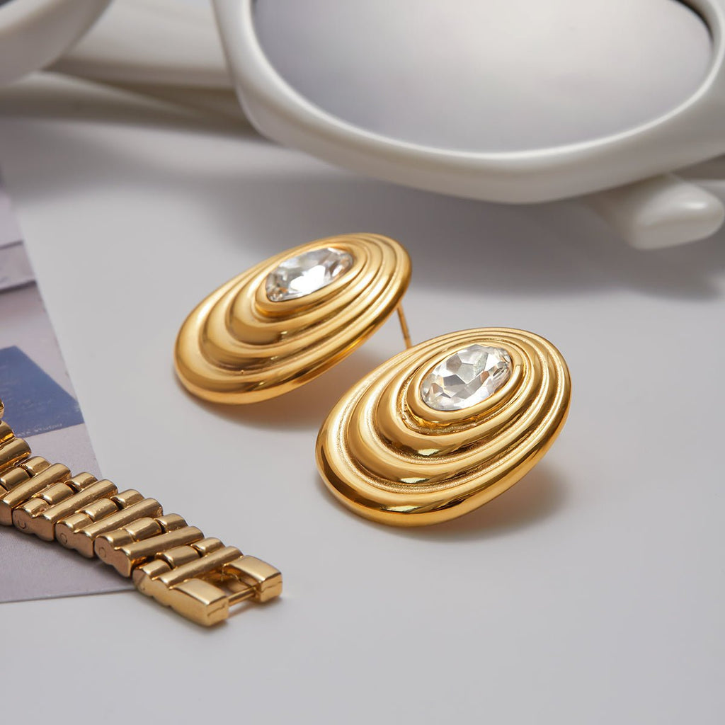 Gold earrings with a watch band on a light background