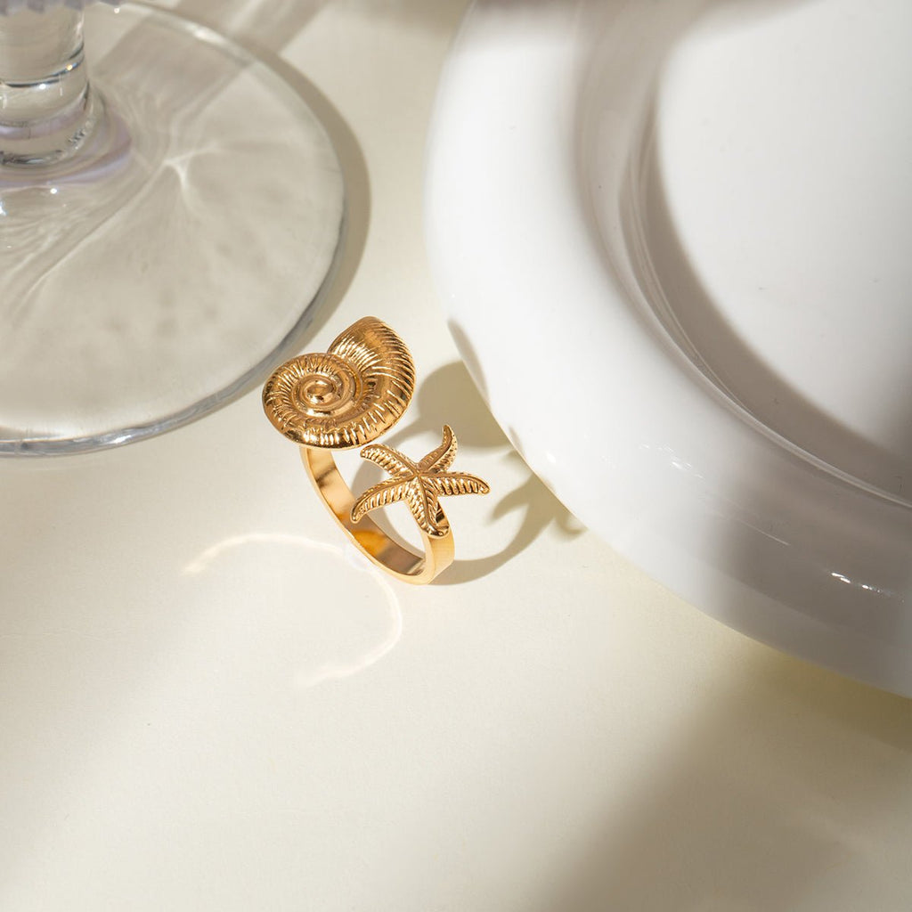 Gold ring with shell design on a white surface