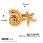Gold ring with shell and starfish design on a white background