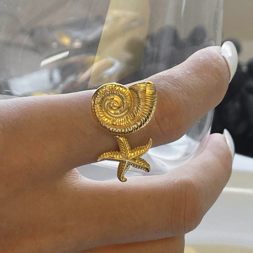 Gold ring with a unique design worn on a finger against a blurred background
