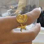 Gold ring with a unique design worn on a finger against a blurred background