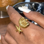 Gold ring with shell and starfish design on a finger