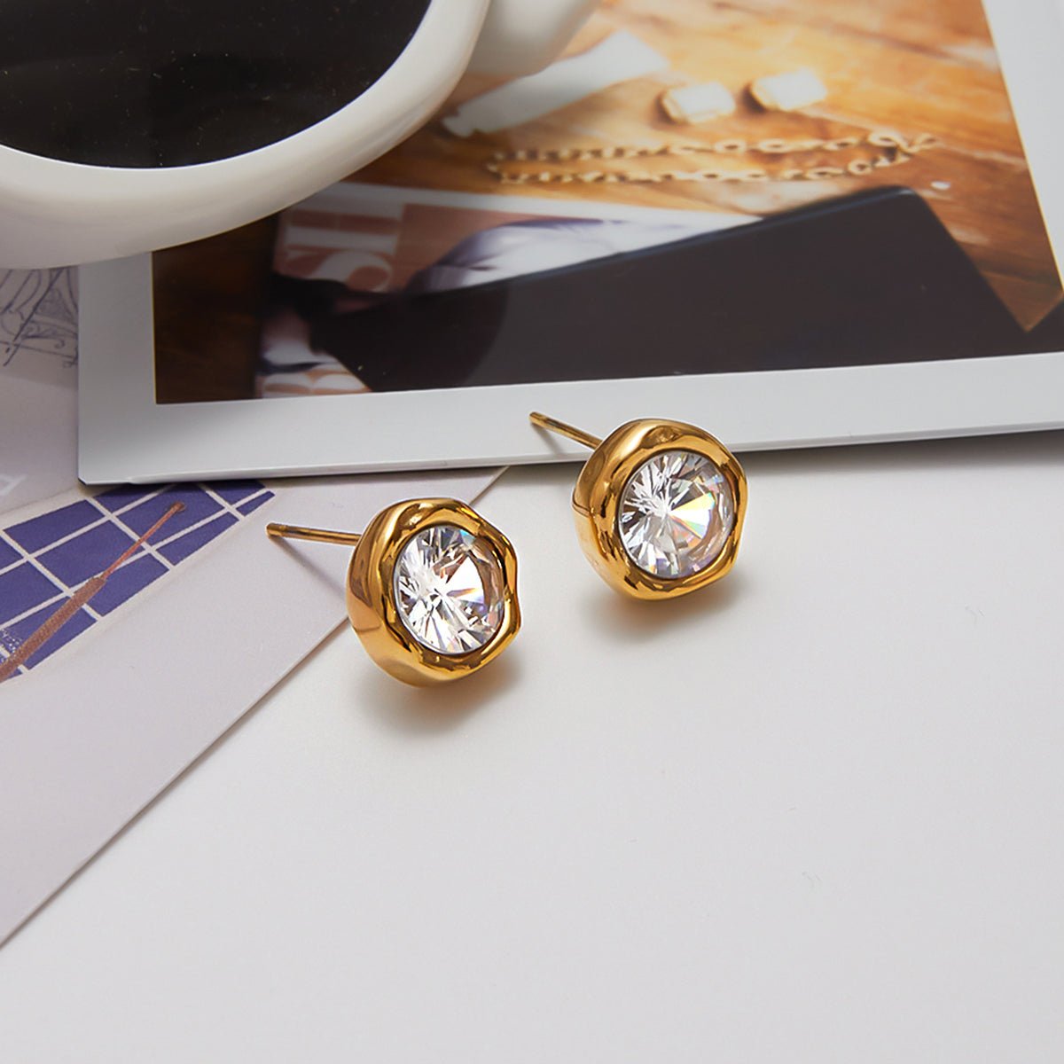 Gold earrings with clear gemstones on a white surface