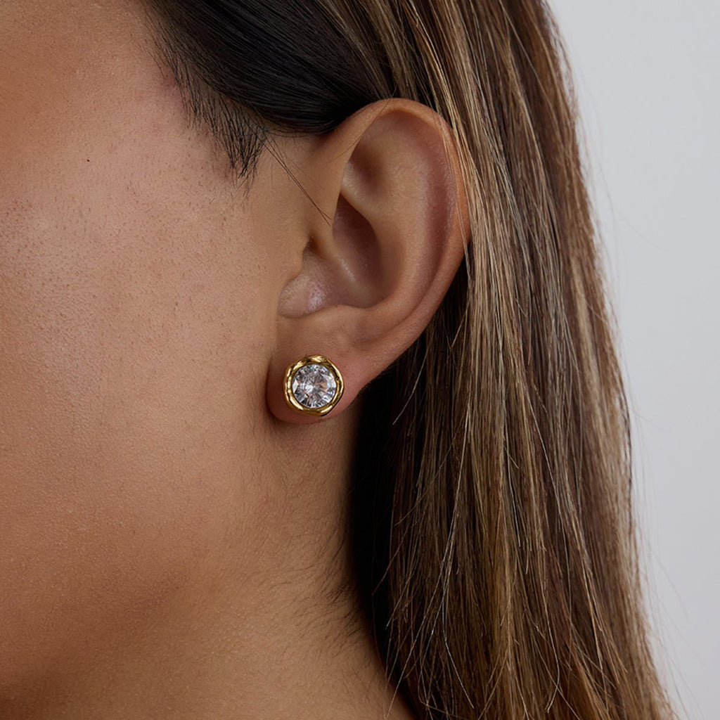 Close-up of round-cut CZ earrings in gold bezel setting