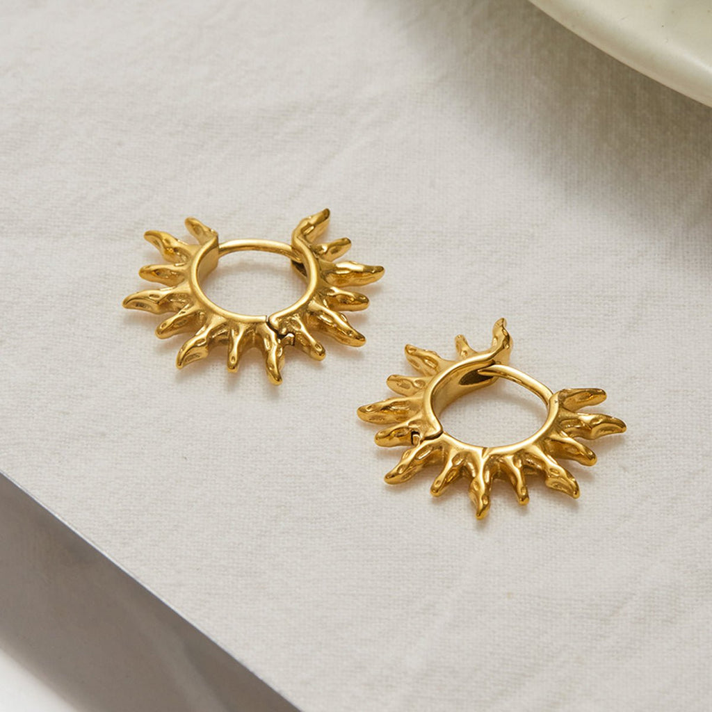 Pair of gold hoop earrings on a light fabric background