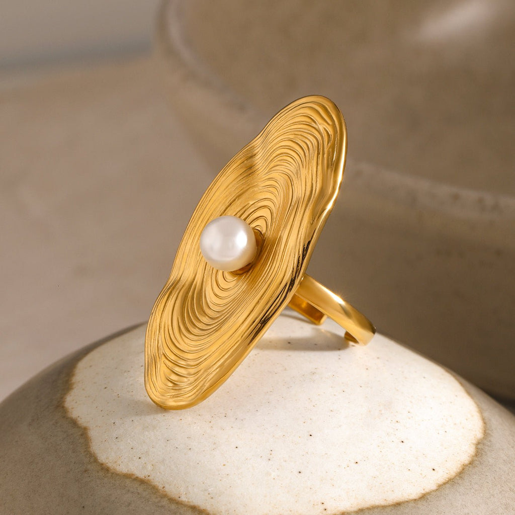 Gold ring with a pearl on a textured surface