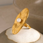 Gold ring with a pearl on a textured surface