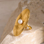 Gold ring with a pearl on a textured stone surface