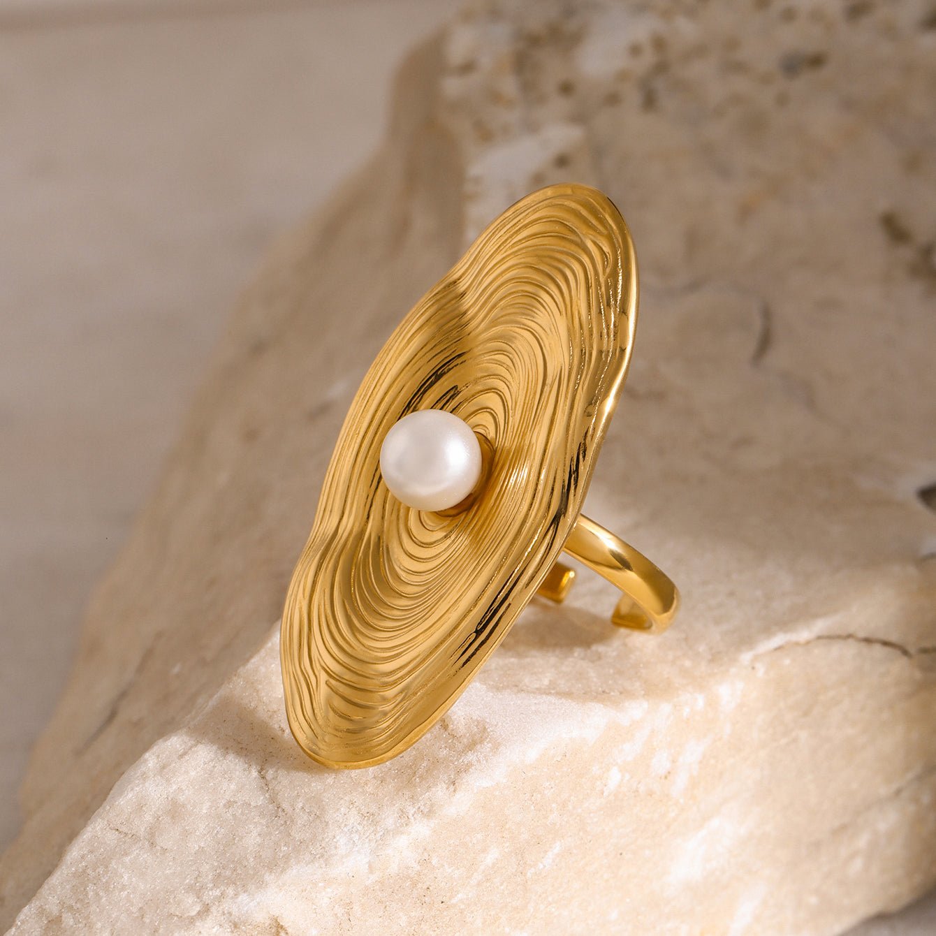 Gold ring with a pearl on a textured stone surface