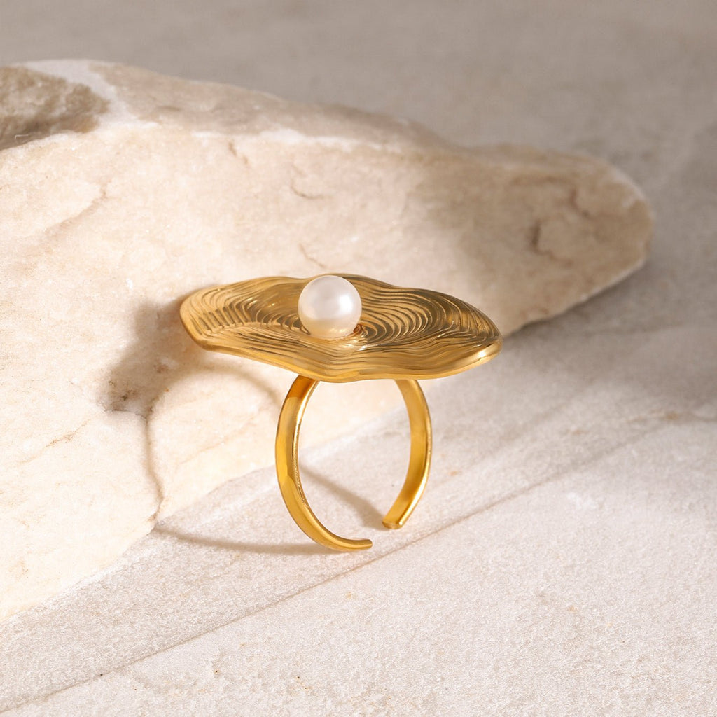 Gold ring with a pearl on a light stone background