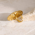 Gold ring with a textured design on a beige stone surface