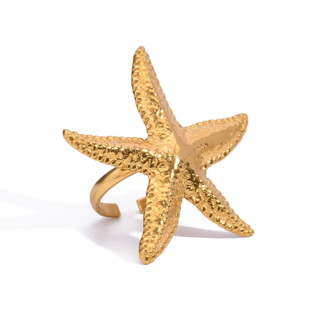 Gold starfish-shaped ring on a white background
