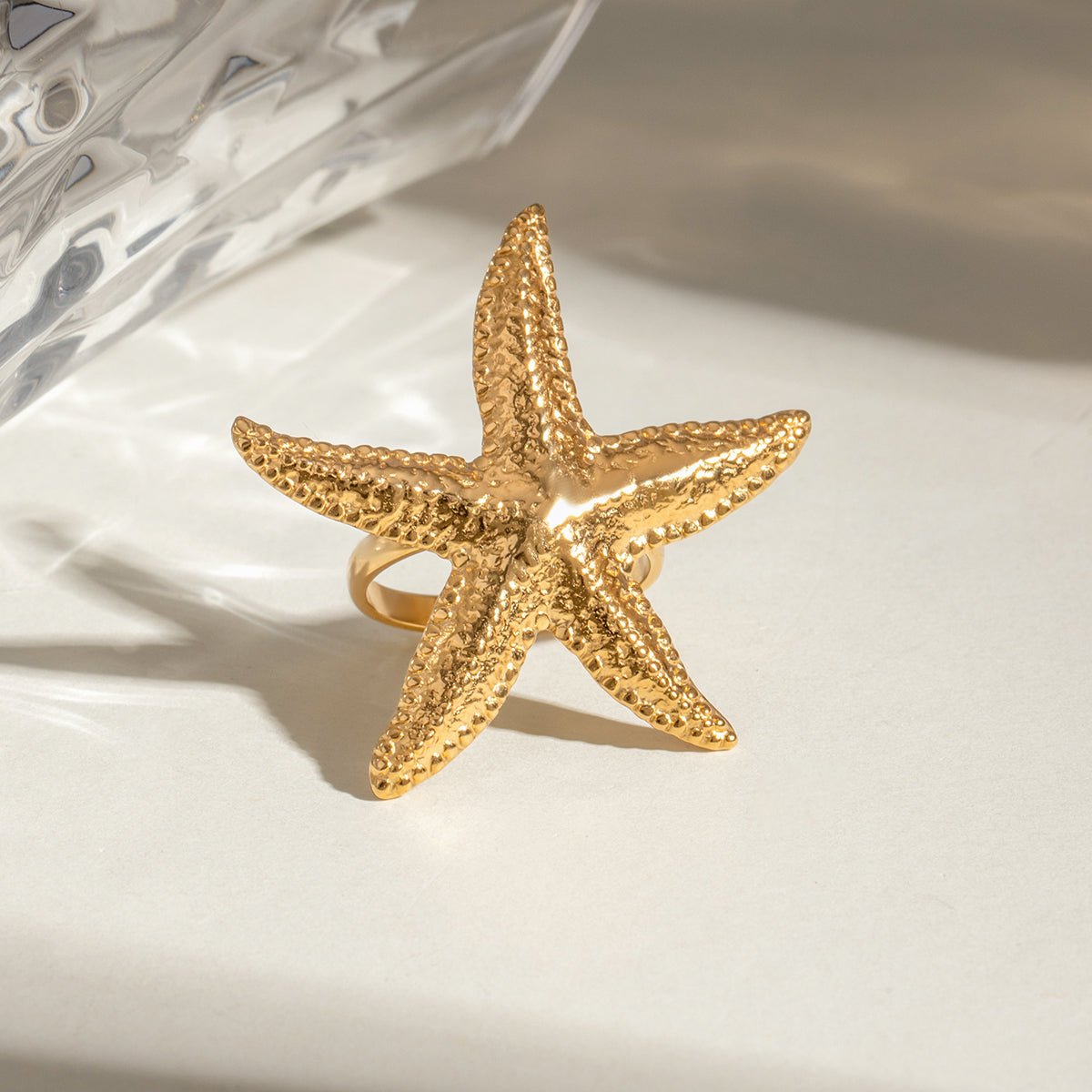 Gold starfish-shaped ring on a light background