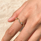 Gold ring with small diamonds on a hand against a beige background