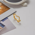 Gold ring with gemstones on a light surface with a cup and matches in the background