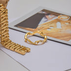 Gold bracelet and ring on a light surface with a blurred background