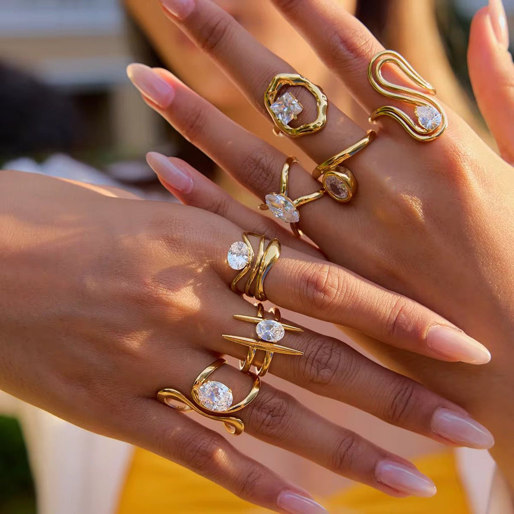 Close-up of hands wearing gold rings with gemstones on a blurred background