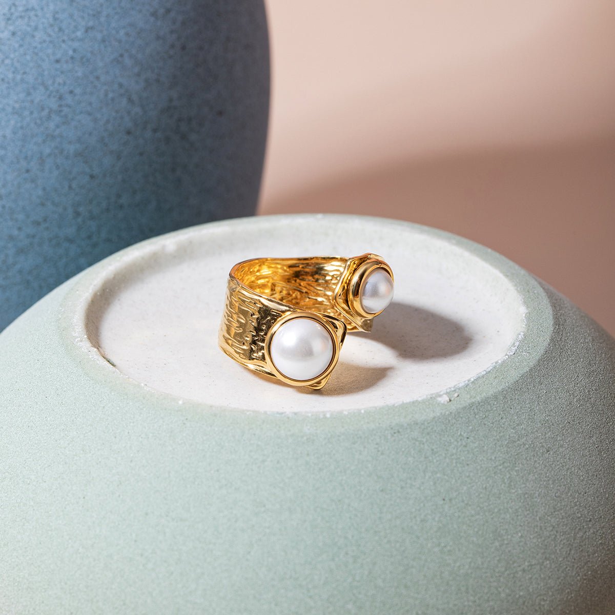 Gold ring with two white pearls on a light blue stand