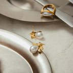 Gold and pearl earrings on a textured surface