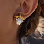 Gold bee-shaped earring with a pearl on an ear