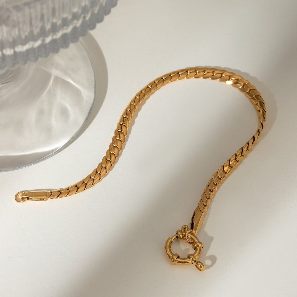 Gold chain bracelet with a clasp on a white surface