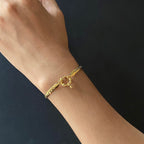 Gold bracelet on a wrist against a dark background