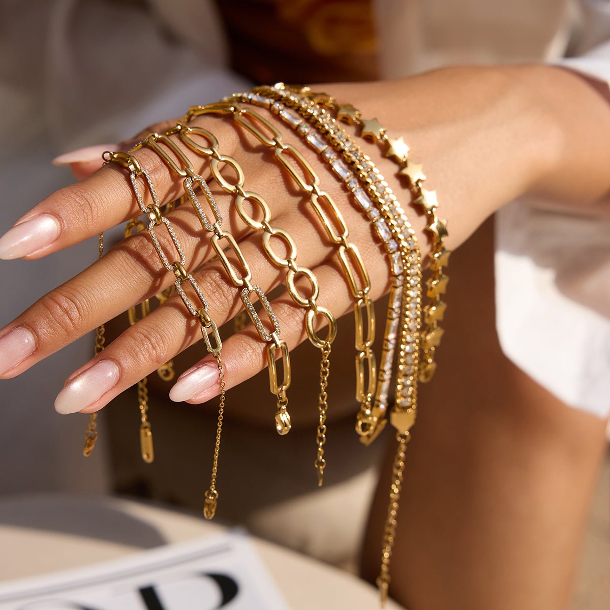 Hand wearing multiple gold bracelets with a blurred background