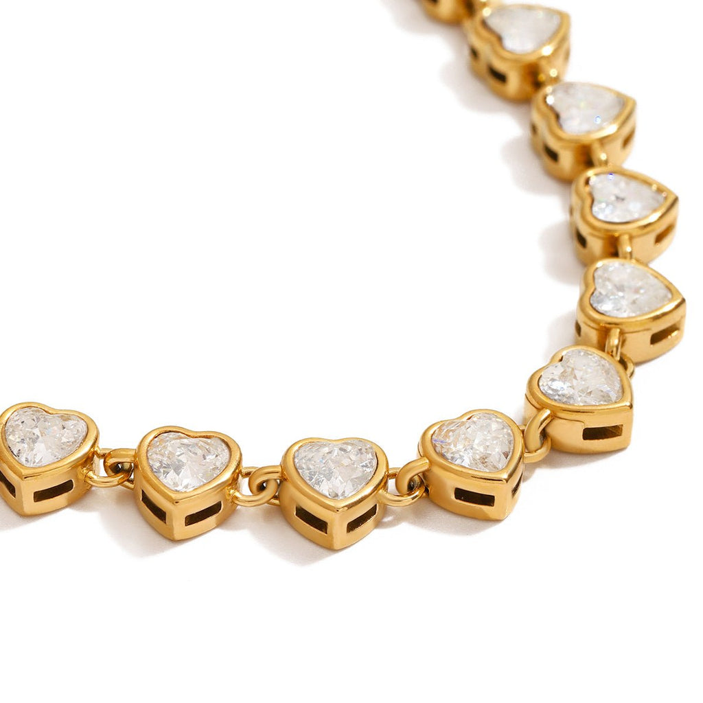 Gold bracelet with heart-shaped diamond-like stones on a white background